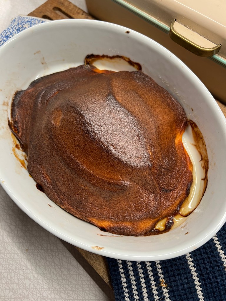 En ugnsform med en bränd yta och delvis smält fyllning, placerad på en kökshandduk.